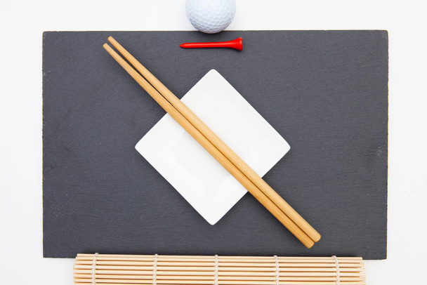 Rectangular slate plate with chopsticks for sushi and golf tee.  - Photo, Image