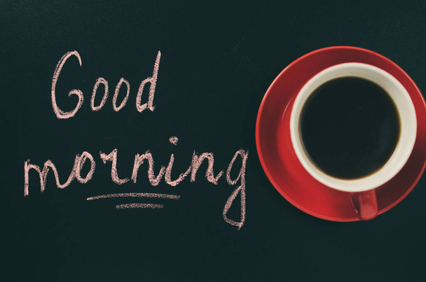 Кубок кави на темному фоні і напис "Доброго ранку". Зображений образ. Вибіркове фокусування. Вид зверху. - Фото, зображення