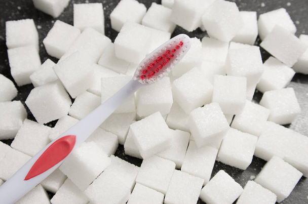 toothbrush on the background of the sugar cubes of refined sugar, preventing tooth decay, caring for the health of your teeth, the causes of caries - Foto, Bild