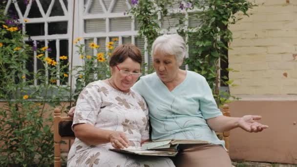 Ηλικιωμένες γυναίκες κοιτάζουν παλιές φωτογραφίες σε ένα άλμπουμ - Πλάνα, βίντεο