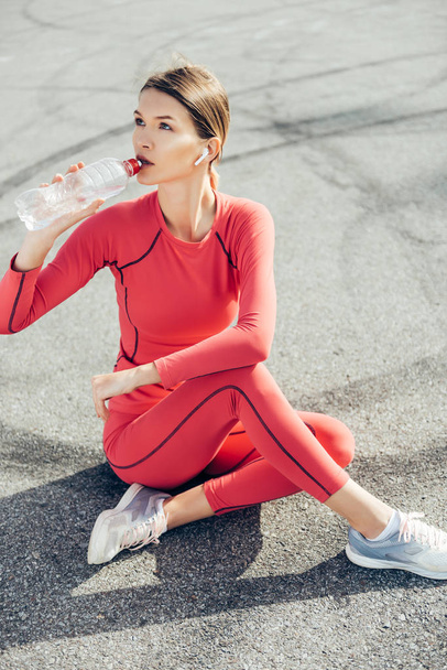 Fit young lady drinking water after workout. - Foto, Bild