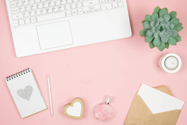 Femine office desktop with office accessories on pink background. Womens workspace with succulent, candle and cosmetics. - 写真・画像