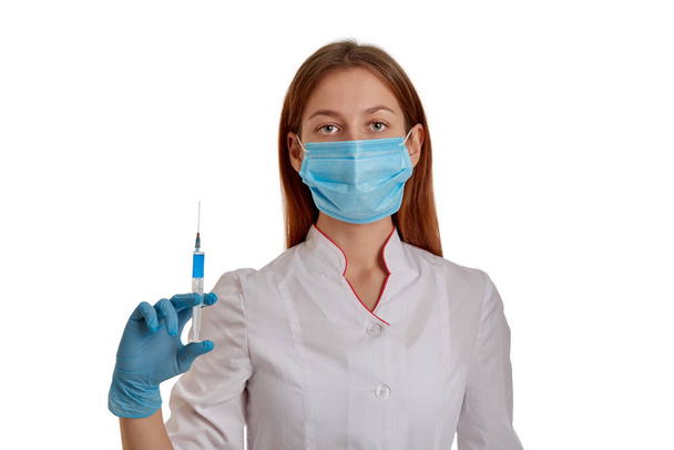 Lekarz trzyma strzykawkę z lekiem na koronawirus 2019-ncov. Pielęgniarka w masce oddechowej chroni się przed szybko rozprzestrzeniającym się koronawirusem z Chin.. - Zdjęcie, obraz