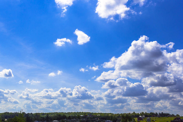 Μπλε καλοκαιρινό ηλιόλουστο ουρανό με άσπρα σύννεφα και το τοπίο του χωριού και του δάσους.. - Φωτογραφία, εικόνα