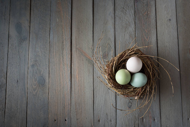 Tender colored easter eggs in a nest on a old shabby wooden table - Foto, immagini