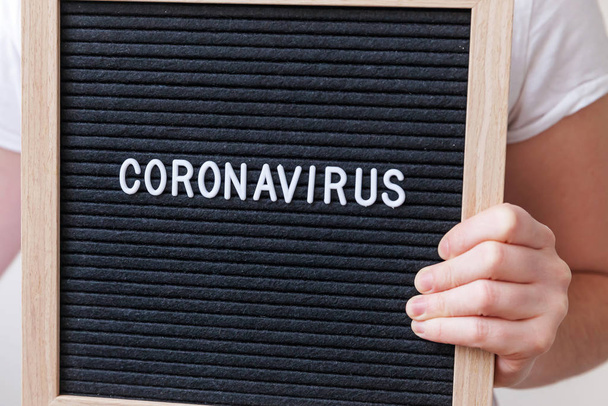 Woman hand holding black letter board with text phrase Coronavirus. Novel coronavirus 2019-nCoV, MERS-Cov middle East respiratory syndrome coronavirus originating in Wuhan China - Foto, imagen