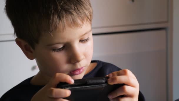 Boy playing video game on mobile phone. Young hacker. Cyber security background. Child and gadget. Facial expression of child with gadget. Video game on mobile phone - Footage, Video