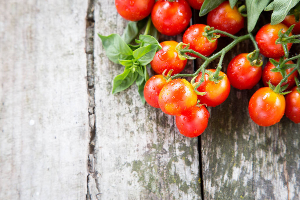 Small red cherry tomatoes on an old wooden table in rustic style, selective focus. - Foto, Bild