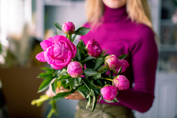 Nahaufnahme Blumen in der Hand. Floristik-Arbeitsplatz. Frau arrangiert einen Strauß mit Rosen, Chrysanthemen, Nelken und anderen Blumen. Floristiklehrerin in Meisterkursen oder Kursen - Foto, Bild