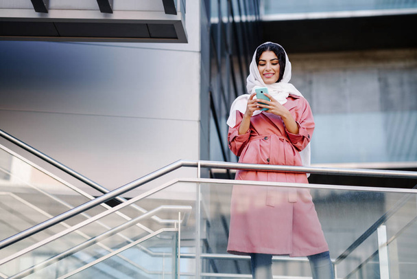 Nuori muslimi nainen yllään hijab tekstiviesti hänen älypuhelin. - Valokuva, kuva