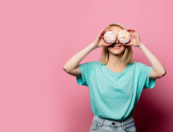 schöne blonde Frau mit Donut auf rosa Hintergrund - Foto, Bild