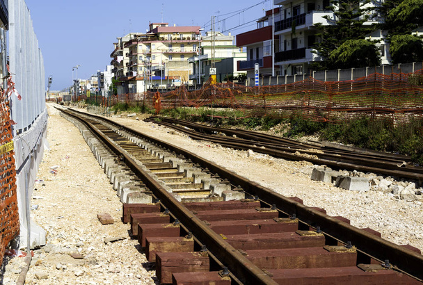 Bau einer neuen Eisenbahnlinie an einem Stadtbahnhof. Die Schienen werden auf neuen Schwellen aus Hartholz verlegt - Foto, Bild