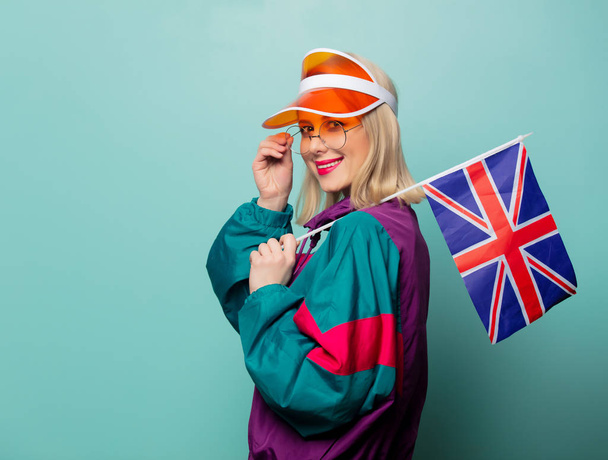 Stijl blonde vrouw in jaren 90 sport pak met Groot-Brittannië vlag op blauwe achtergrond - Foto, afbeelding
