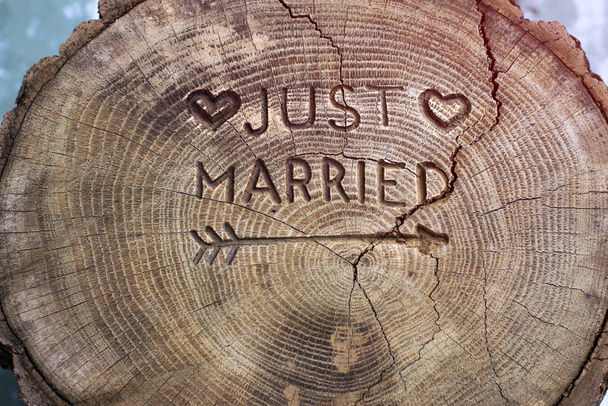 Μόλις παντρεύτηκα. Μια επιγραφή σε ένα κόψιμο δέντρου για γαμήλια διακόσμηση. Χειροποίητο διακοσμητικό ξύλο δρυός. Φωτογραφία για το σχεδιασμό πρόσκλησής σας. - Φωτογραφία, εικόνα