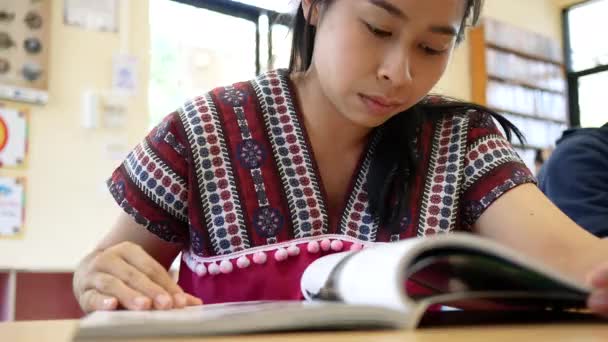Aasialainen nainen lukee kirjaa kirjastossa huoneessa
. - Materiaali, video