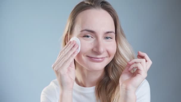 Beautiful woman cleaning her face with cotton pads. Skin care and beauty concept. - Imágenes, Vídeo