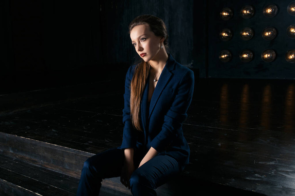 Studio portrait of a businesswoman in suit, against dark background - Photo, image