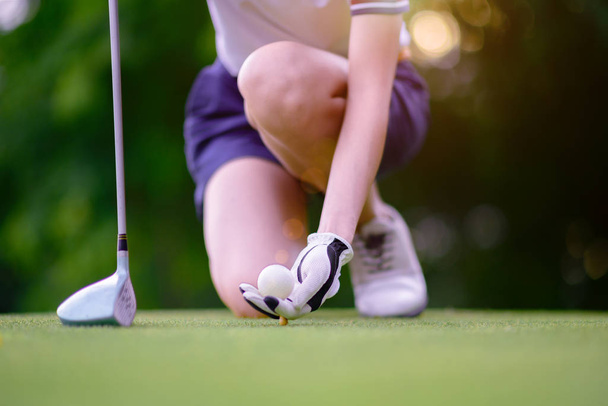 hand of young woman golf player holding golf ball push on wooden tee, ready to hit the ball to the destination target - Φωτογραφία, εικόνα