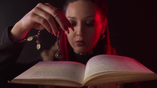 Widok z przodu czarownicy z amuletem trzymając otwartą magiczną księgę - Materiał filmowy, wideo