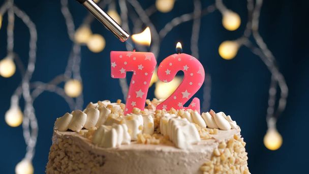 Birthday cake with 72 number candle on blue backgraund set on fire by lighter. Close-up view - Fotoğraf, Görsel