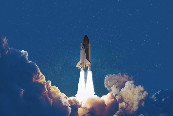 Космический корабль взлетает в звездном небе на классическом голубом фоне. Цветовая концепция. Ракета на старте
  - Фото, изображение
