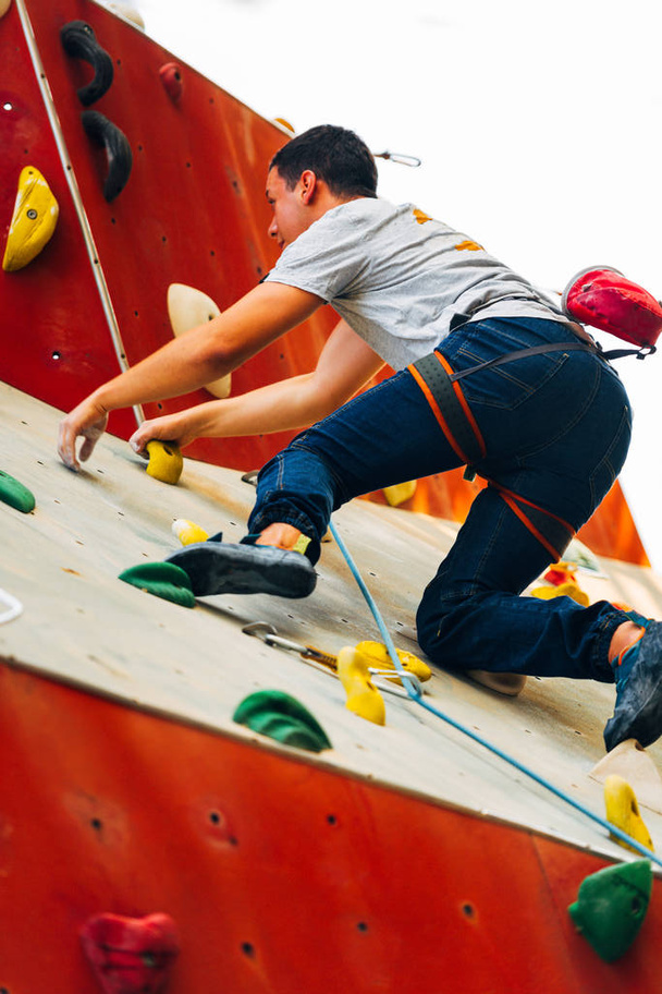 Junger sportlicher Mann klettert auf Übungswand im Freien - Foto, Bild