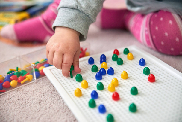 toddler plays with colorful pins - Foto, afbeelding