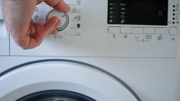 Man Using a Laundry Machine Modern Appliance for Washing and Cleaning Dirty Clothes - Foto, Imagen