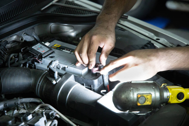 Mechanic inspect and replace car battery at garage - Photo, image