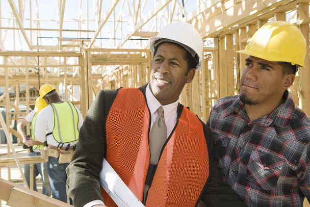 Építész művezető ellenőrző keret és a férfiak dolgoznak a háttérben az építési területen - Fotó, kép