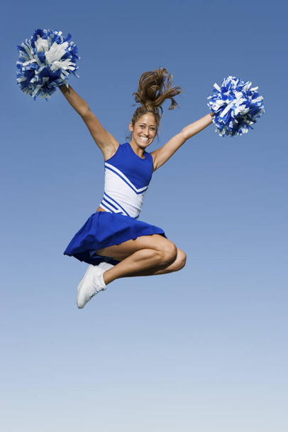 Full length of a young cheerleader jumping against clear sky - Photo, image