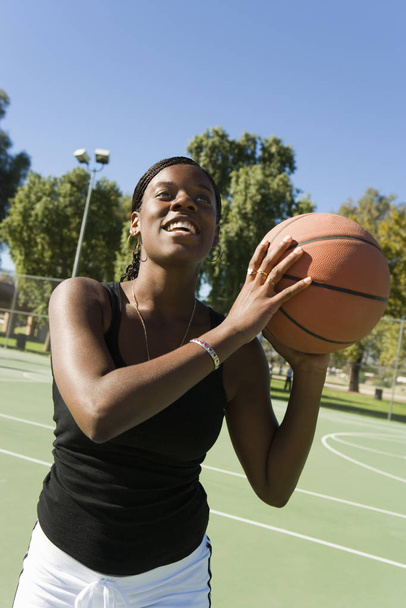 Happy African American woman with basket ball in court - Фото, зображення