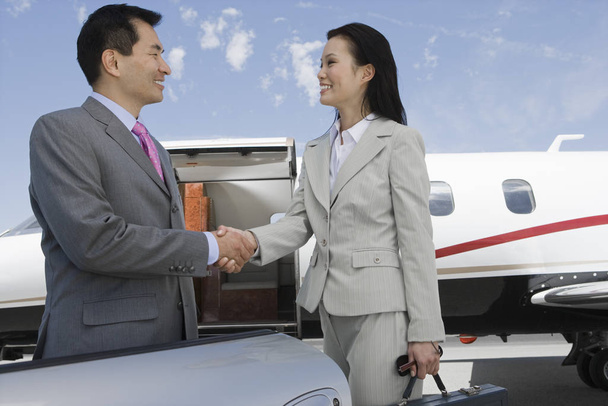 Happy Korean businesswoman and Japanese businessman meeting at the airport - Foto, Imagem
