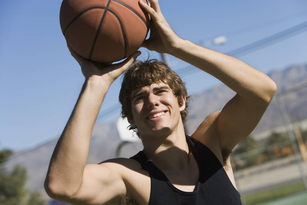 Happy young man taking a penalty shot with basketball - Foto, Imagem