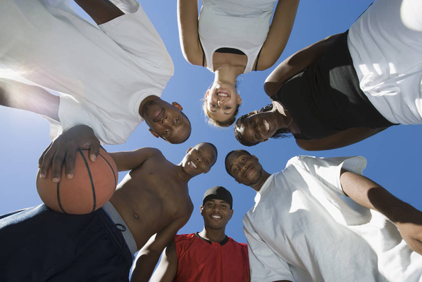 Happy multiracial group of friends with basketball against sky - Foto, Imagen