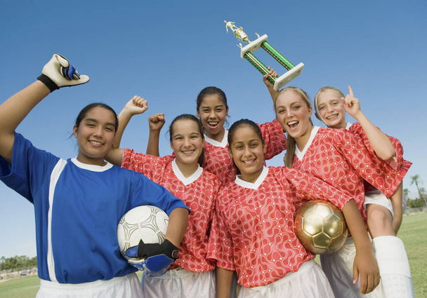 Group portrait of excited female soccer players holding winning trophy - Photo, image