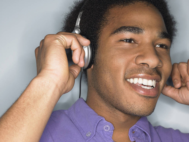 Closeup of African American young man listening music through headphones - Fotografie, Obrázek