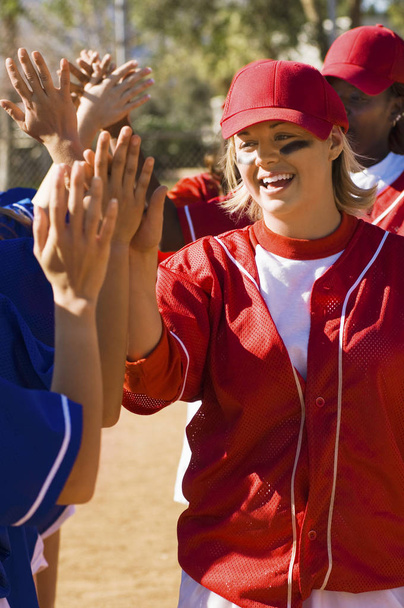 Female baseball players giving high five after a winning game - Foto, imagen