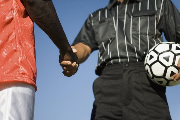 Midsection of football player shaking hand with referee - Foto, Imagen