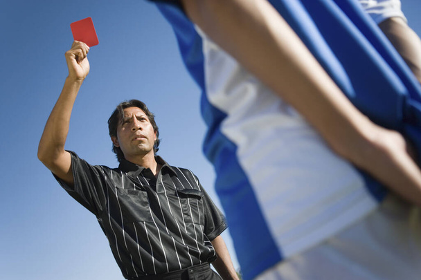 Low angle view of referee indicating red card dismissal to player - Foto, Imagen