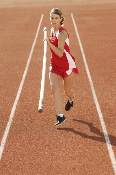 Full length of female pole vaulter running with pole on track and field - Fotografie, Obrázek