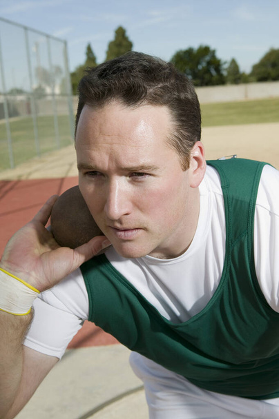 Male athlete ready to throw shot put on track and field - Foto, Imagem