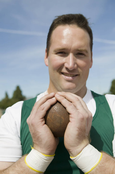 Close-up of male athlete holding shot put - Foto, afbeelding
