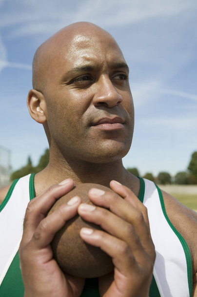 African American male athlete with shot put looking away - Fotó, kép