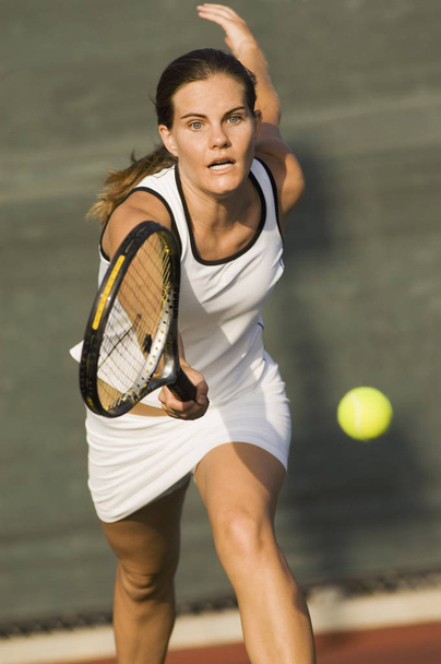 Sporty female tennis player running ahead for a shot on tennis court - Photo, image