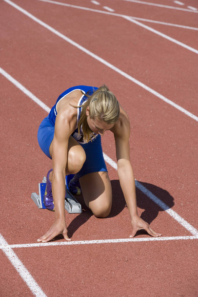 Full length of Caucasian female athlete ready to race on track and field - 写真・画像
