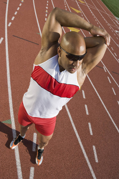 Full length of an African American male athlete stretching on race track - Foto, Bild