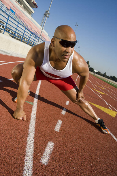 Full length of an African American male athlete warming up on race course - Foto, Imagem
