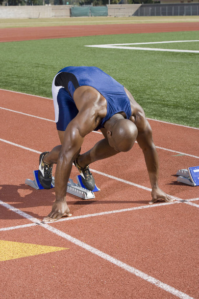 African American male athlete in starting position on running track - Photo, Image
