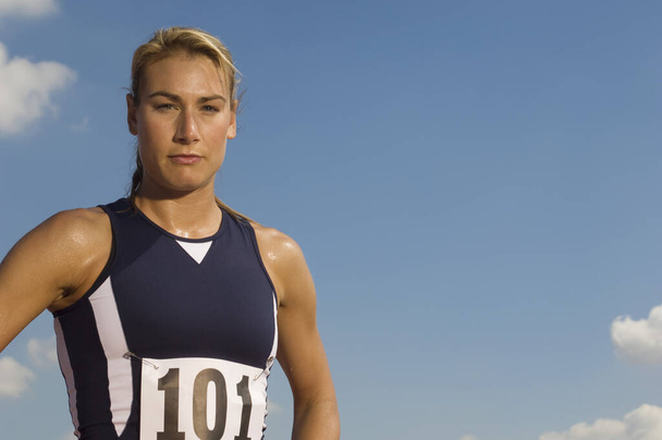 Portrait of a confident female athlete in sportswear against sky - Фото, изображение